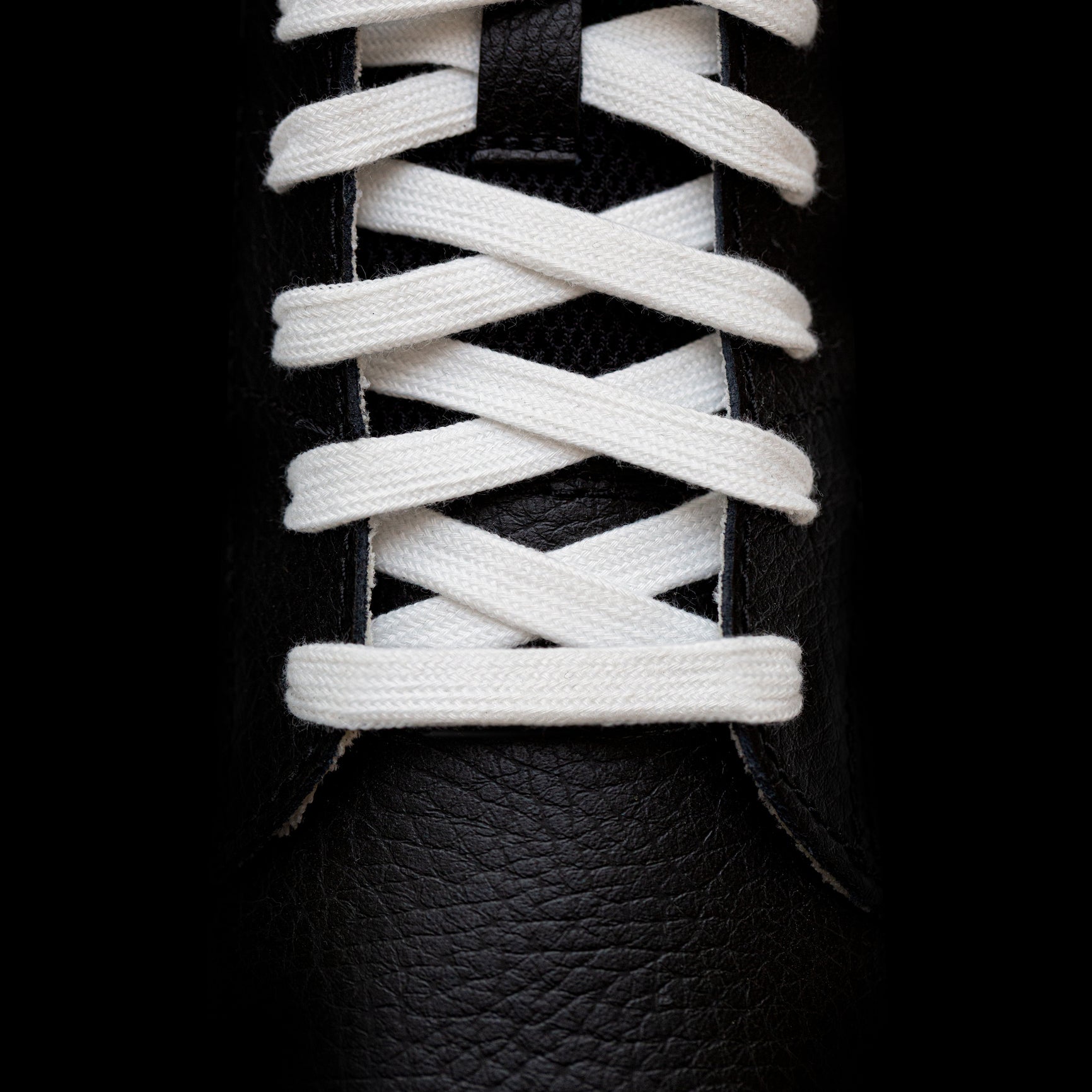 White athletic shoelaces in black sneakers